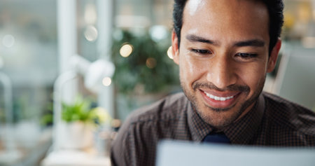 Asian, research and businessman in office with smile for typing, creative agency or self publishing. Online, writer or worker with laptop, computer or pc for editing of ebook novel with technologyの写真素材