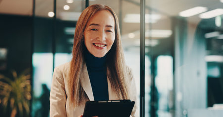 Mature woman, tablet and research for business, communication or portrait in office with night. Manager, technology and Japan for networking acquisition, performance review or proposal with kpi toolsの写真素材