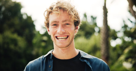 Portrait, happy man and college student in park on campus for university, opportunity and studying. Laugh, smile and male person in nature with pride for school, education and ecology scholarshipの写真素材