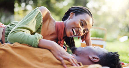 Laugh, nature and love with black couple and picnic for bonding, happiness and romantic date. Funny, support and conversation with man and woman at park for commitment, valentines day and summerの写真素材