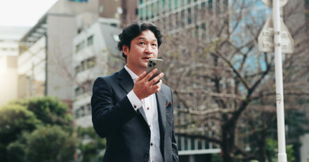 Japanese, business and man with phone speaker for discussion, schedule update and negotiation chat. Male person, mobile sound and communication of audio, contact information and urban travel in Japanの写真素材