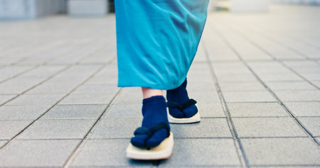 Legs, slippers and walking in city street with traditional clothes, outfit and fashion for heritage. Person, feet and shoes for style, culture and kimono for travel, sightseeing or adventure in Japanの写真素材