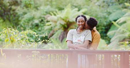 Kiss, hug and black couple on bridge in park for bonding, love connection and outdoor adventure. Commitment, man and woman on path in nature for romantic date, weekend embrace and happy green garden.の写真素材