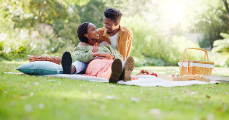 Food, relax and love with black couple and picnic for bonding, happiness and romantic date. Smile, support and conversation with man and woman at park for commitment, valentines day and summerの写真素材