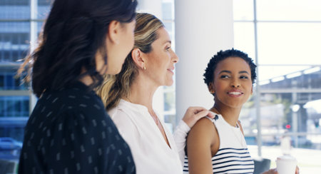Business women, attorney and walking in office building with taking, conversation and discussion. Female people, colleagues and diversity as lawyers in law firm, together or collaboration as teamworkの写真素材