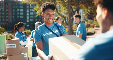 Box, volunteer team and man outdoor for donation, help and community care. NGO group, smile and charity service with package for distribution, food drive and humanitarian aid with poverty suppliesの写真素材