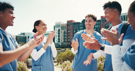 Medical success, students and happy with applause outdoor for health training feedback or board exam results. Diversity, people or celebration in circle for healthcare practice and residency approvalの写真素材