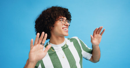 Dance, smile and fashion with man in studio for celebration, freedom and gen z with cool style. Happiness, energy and afro hair with male person on blue background for hip hop music, audio and funの写真素材