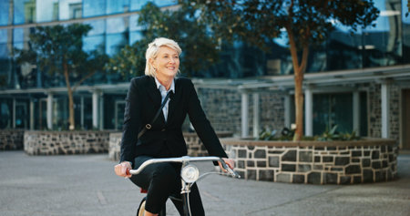 Bicycle, smile and mature businesswoman in city with travel, journey or trip to office building. Commuting, happy and professional female executive with eco friendly transport to work in urban town.の写真素材