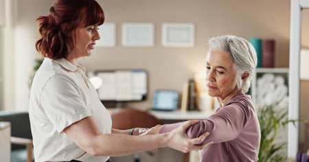 Physio, arm and senior woman with injury support, patient and rehabilitation in clinic with stretching. Physical therapy, helping and healing assessment of doctor with arthritis care and joint checkの写真素材