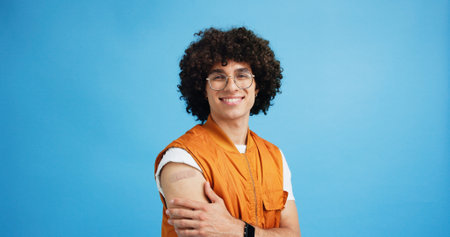 Man, portrait and plaster in studio for healthcare, injection wound and proud guy on blue background. Male person, mockup space and vaccination awareness for disease prevention, bandage and treatmentの写真素材