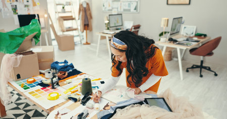 Fashion designer, woman and sketch at desk for planning clothing design and choosing fabric for product sample. Small business, entrepreneur and draft template for creative inspiration or sewing infoの写真素材