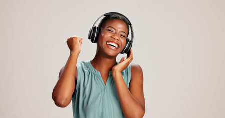 Dancing, woman or happy with headphones on studio background for radio app, enjoyment or movement. Audio playlist, black person or excited with music, online sound or streaming subscription on mockupの写真素材