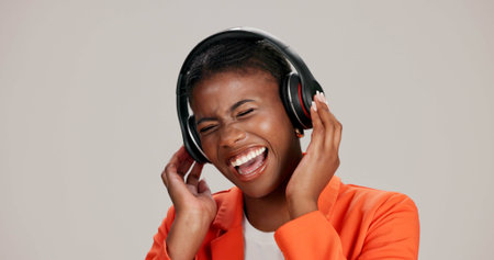 Black woman, headphones and hearing music in studio, streaming hip hop album and white background....