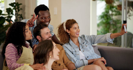 Friends, excited and selfie for football game, socializing and reunion in living room on couch. Diverse group, people and happy for soccer streaming, social media update and smiling for photographyの写真素材