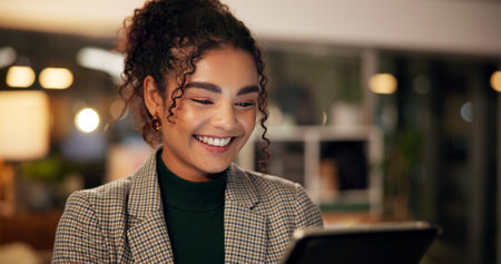 Smile, reading and tablet with business woman in office for online review, client feedback and success. Happy, overtime and media agency with person in startup at night for design trends and researchの写真素材