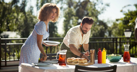 Garden, friends or happy at food for social, gathering or outdoor for New Years celebration. Woman host, man or serving lunch at party for reunion, sharing meal or bonding at table in holiday seasonの写真素材