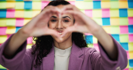 Happy woman, portrait and heart hands in office for business, agenda or career passion with creativity. Designer, love emoji or smile at sticky notes for timeline, job development or pride in companyの写真素材