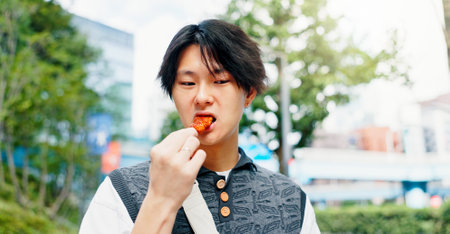 Street food, eating and travel with Japanese man in city for chicken teriyaki, hunger and nutrition. Health, traditional cuisine with culture with person and skewer snack in Japan for lunch and tripの写真素材