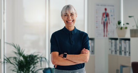 Woman, physiotherapist and portrait in office with confidence, career pride and healthcare service. Mature chiropractor, happy and about us in practice for reflexology, arms crossed and physiotherapyの写真素材