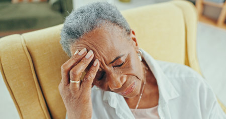 Sad, senior and thinking with black woman on sofa for reflection, depression and retirement. Dementia, memory and regret with elderly person in living room of nursing home for grief, lonely and tiredの写真素材
