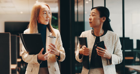 Japanese, lawyers or people in office walking with coffee, folder or documents for funding review. Teamwork, morning or women speaking at law firm for legal project, case feedback or profit portfolioの写真素材