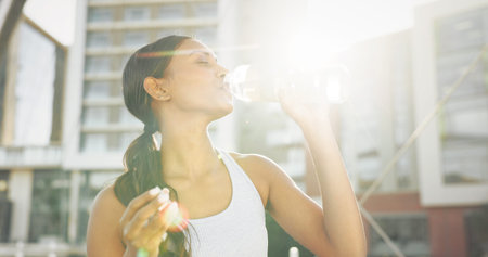 Woman, drinking water and city athlete on break, liquid nutrition and sports drink for fitness....