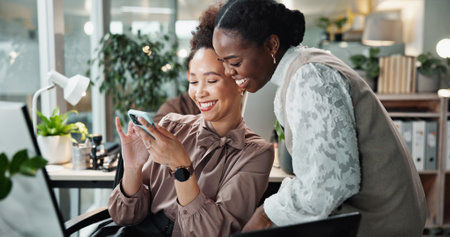 Business, women and laughing with phone at desk for funny website review, social media post or corporate meme. Designer, employees and showing smartphone in office for project research or online jokeの写真素材