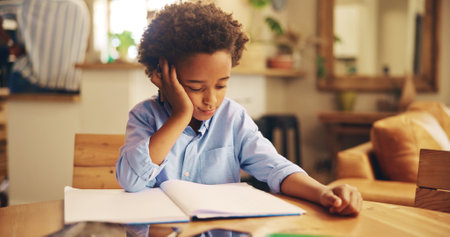 African boy, books and bored with homework, frustrated or learning disability with thinking in family home. Kid, notebook and annoyed with reading, study or tired with dyslexia for education in houseの写真素材