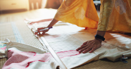 Woman, hands and fashion designer with material for garment, fabric or clothing on floor at boutique. Japan, closeup or seamstress with apparel, textile or texture for tailoring or dress makingの写真素材