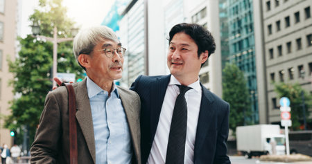 Asian, walking and business people in city talking for conversation, travel or bonding. Smile, discussion and professional Japanese colleagues speaking of urban project together commuting in Tokyoの写真素材