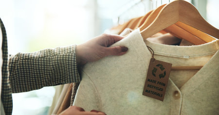 Shopping, store and hands with clothes on rack for recycling, sustainability and eco friendly material. Fashion, boutique and person with tag on textile, clothing and fabric for retail choiceの写真素材