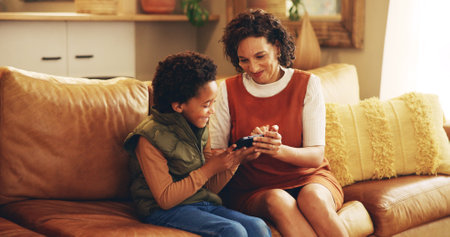 Mother, child and happy with tablet on sofa for teaching online app, playing educational games and bonding. African people, woman and boy kid in home with digital tech for internet browsing and relaxの写真素材
