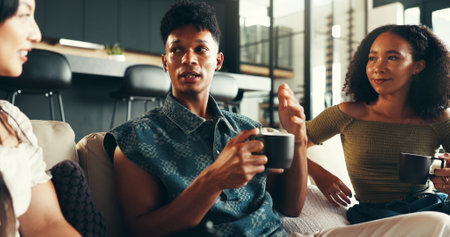 Bonding, conversation and friends with coffee, home and listening to gossip, couch and drinks in living room. Happy, talking and relax in lounge, tea and together in weekend, smile or people in houseの写真素材