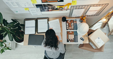 Above, woman and planning in office for architecture, design process or blueprint for housing development. Engineer, moodboard or creative at desk for building renovation, project management or ideasの写真素材