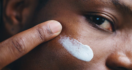 Face, skincare lotion and black man apply moisturizer for treatment and beauty. Portrait, cosmetics product and closeup of cream for dermatology, facial sunscreen and under eye hydration applicationの写真素材