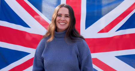 Portrait, smile and woman with British flag for national pride, support and union jack. Face, happy and girl with uk banner on background for patriotism, sports fan and culture in United kingdomの写真素材