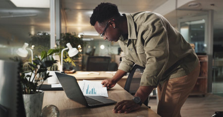 Night, research and documents with business black man in office or financial report, investment and revenue data. Budget, planning and paperwork with person for review, broker and asset managementの写真素材