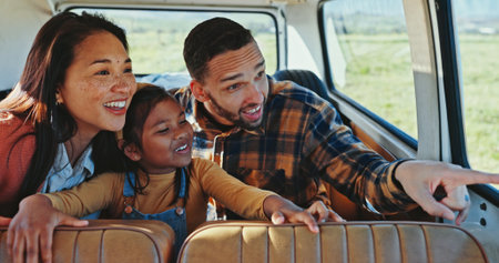 Pointing, road trip or van with child, family and view for sightseeing journey or countryside travel. Happy, interracial or girl bonding for adventure, holiday or vacation with car, mom or dadの写真素材