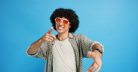 Happy man, portrait and sunglasses with fashion or funky style on a blue studio background. Male person, hipster or young model with stylish shades or cool attitude for summer party or New Year moodの写真素材
