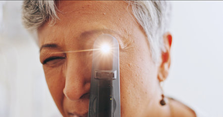Optometrist, pov and retinoscope with mature woman in clinic for eye exam, healthcare and vision. Medical, ophthalmologist and glaucoma test with person and tools for retina, light and assessmentの写真素材