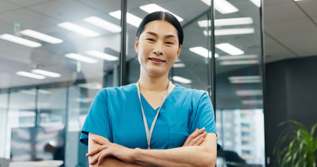 Portrait, woman and surgeon with confidence in hospital for healthcare services, about us and medical advice. Person, nurse and arms crossed of career ambition, diagnosis and treatment trust in Japanの写真素材