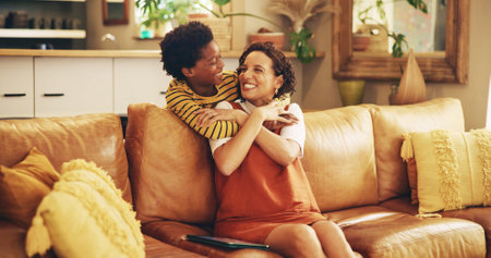 Happy mom, son and hug with love on sofa for bonding, support or care for holiday together at home. Parent, child or kid with smile for embrace, childhood or enjoying mothers day on couch at houseの写真素材