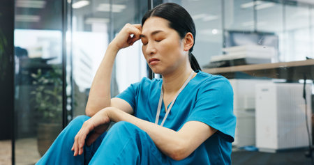 Japanese, woman and nurse with depression in hospital for healthcare stress, medical mistake and burnout. Surgeon, headache and anxiety with surgery crisis, bad news and treatment disaster in Japanの写真素材