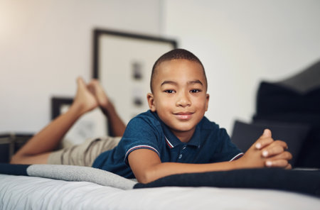 African child, confident and portrait in bed in home to relax for peace, growth and youth development in apartment. Face, adorable and boy resting for calm break and comfort on mattress in Tunisiaの写真素材