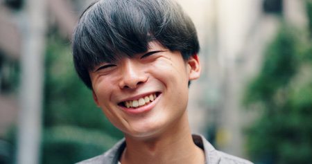Laugh, happy and portrait of Asian man in city for university, education and commute to college. Travel, urban town and face of person on street for holiday, break and weekend in Japan outdoorsの写真素材