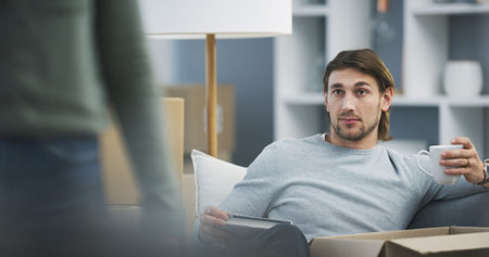 Home, sofa and man with coffee for book, unpacking and thinking in modern apartment with beverage. House, partner and male person with espresso cup for property investment, moving and break on couchの写真素材