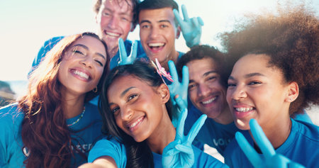 Happy people, portrait or volunteer with peace sign for selfie, community service or eco friendly environment at beach. Group, friends or NGO organization with team for photography, picture or memoryの写真素材