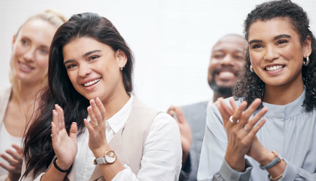 Putting their hands together. Cropped shot of two attractive young businesswoman and their colleagues applauding while attending a seminar in the boardroom.の写真素材