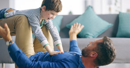 Father, boy and airplane on floor in home, game and playful with smile, knees and bonding with love in lounge. Dad, child and lifting for plane, flight or excited with laugh on carpet in family houseの写真素材